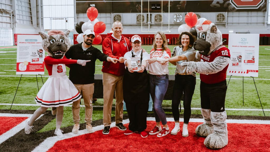 一群人拿着一个大好的咖啡袋摆姿势