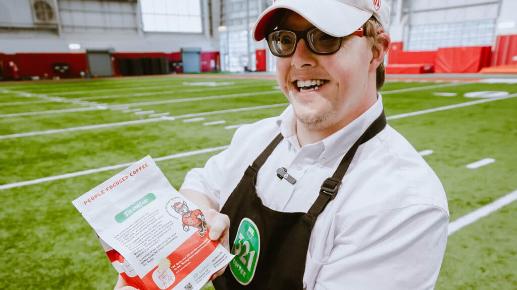 321咖啡公司的员工山姆拿着一个大好的咖啡包，上面印着他的名字、脸和语录