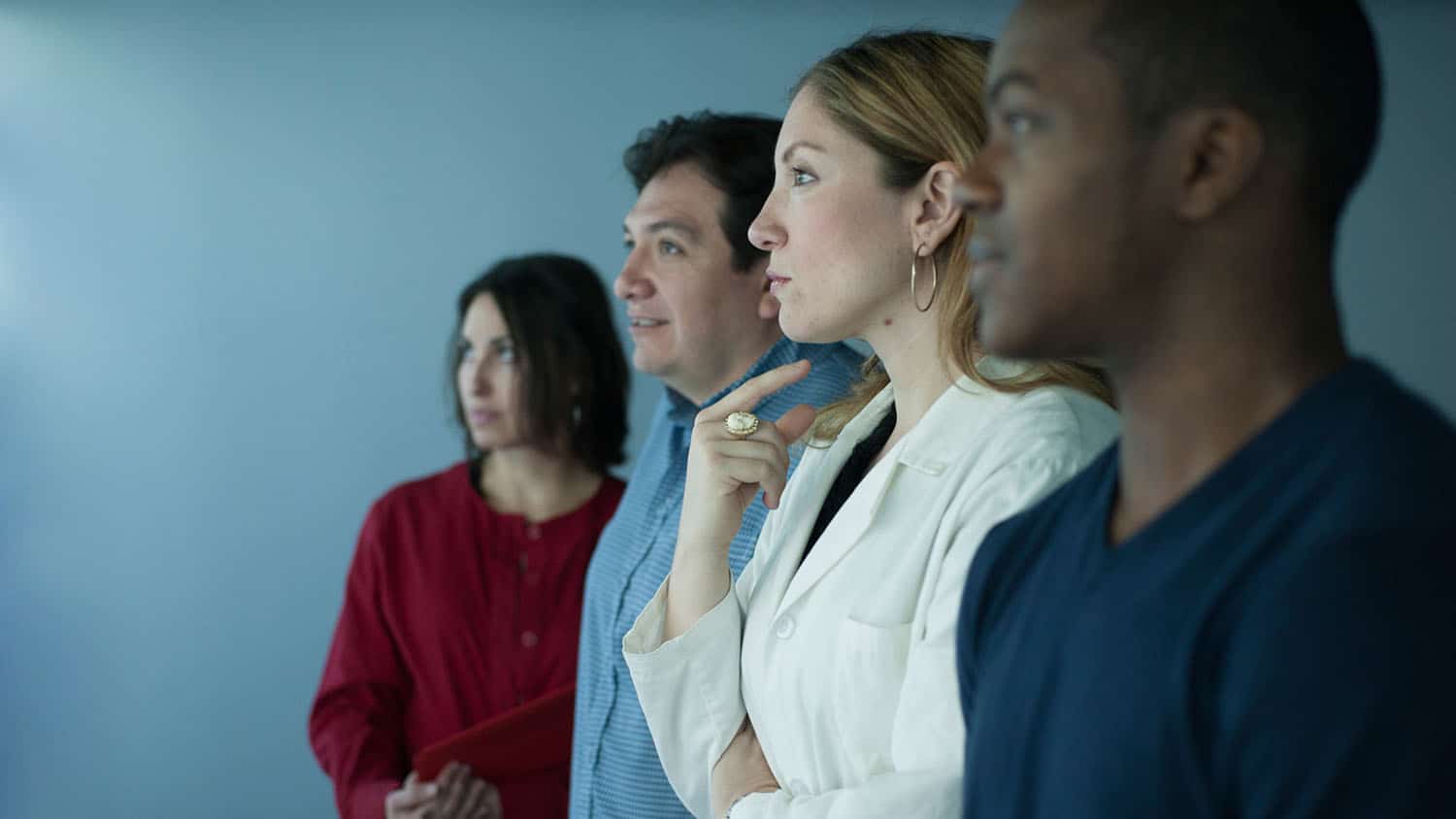 Four faculty researchers stand shoulder to shoulder while looking intently at something to the left of the frame.