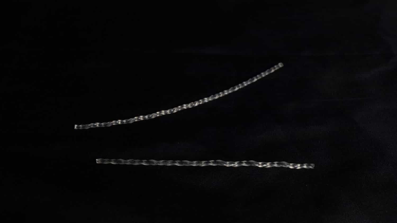 image shows two long, twisted strands of clear polymer