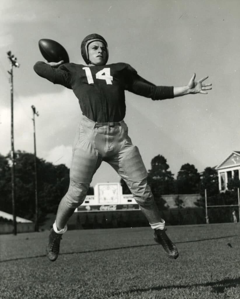 An NC State football player throws a pass in front of the scoreboard in Riddick Stadium in 1935