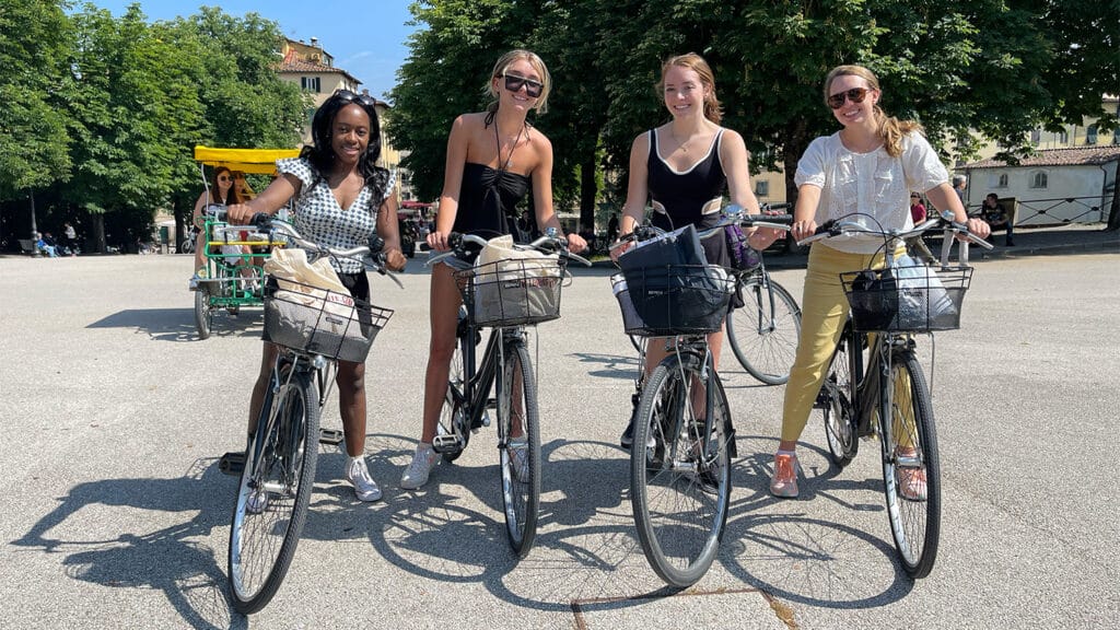 Four female students sitting on bikes in the middle of an empty road