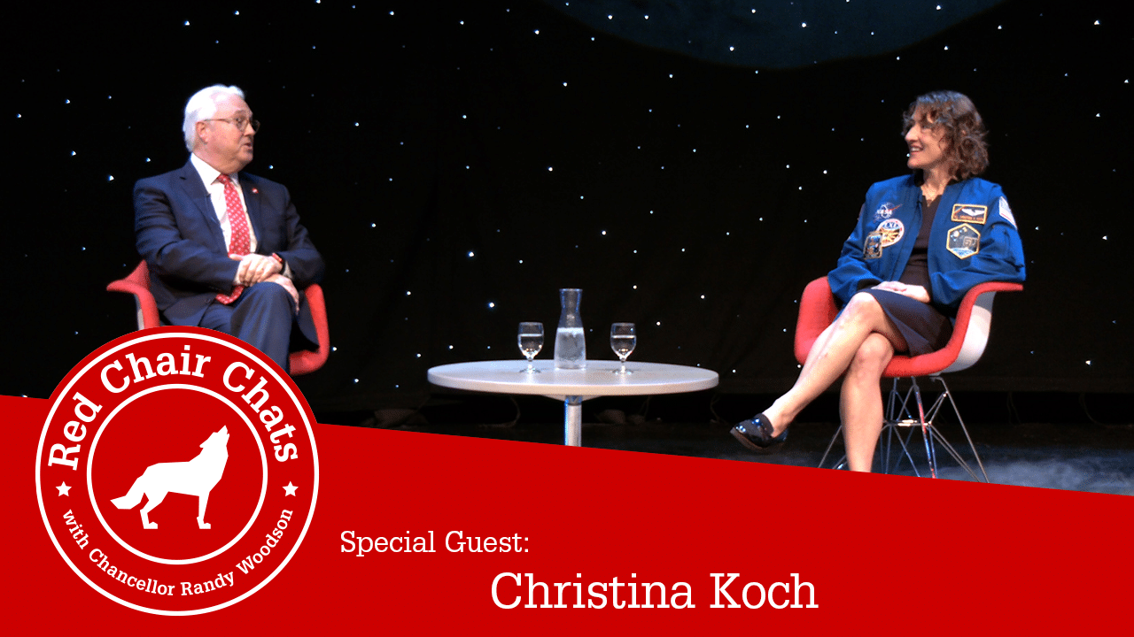总理Woodson和美国航天局宇航员Christina Koch坐在Stewart剧院前台并带星际背景图像中还包含红会聊天图形
