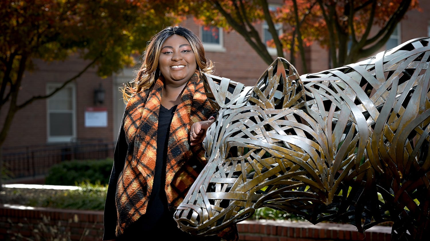 学生开学扬声传送学生奇技Holder站在铜狼雕像旁