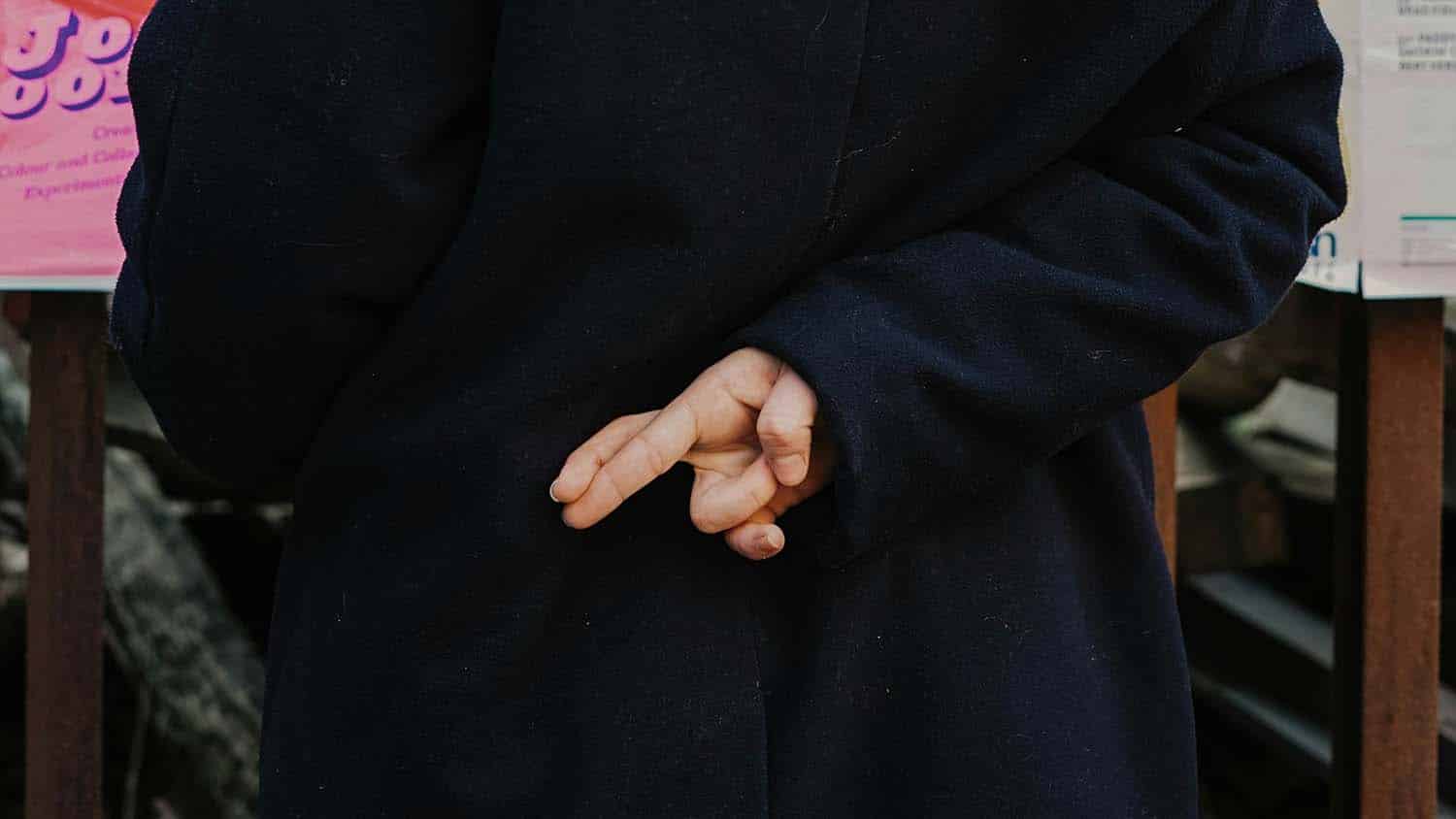 穿黑大衣的人背后交叉指针